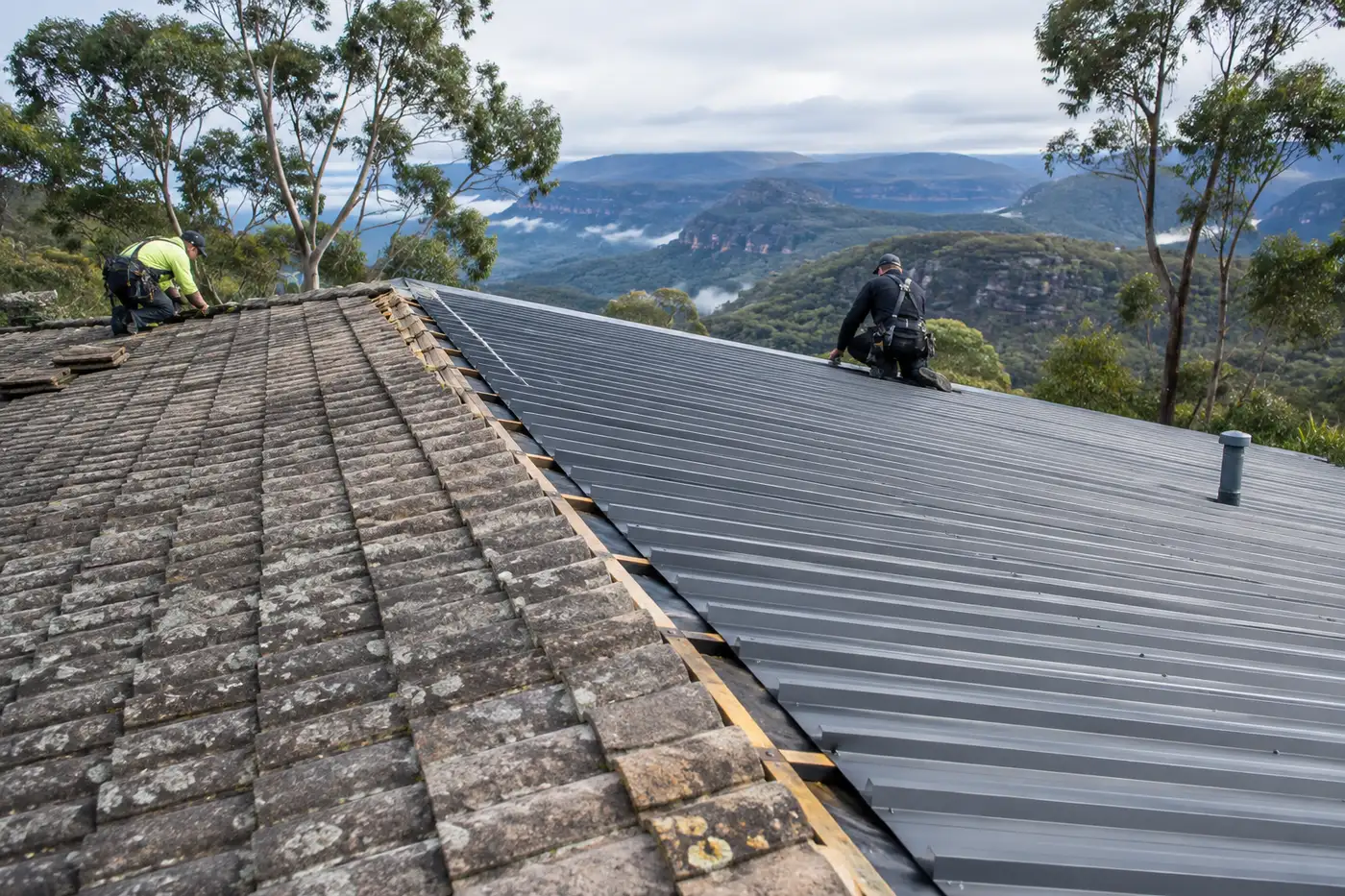 A Blue Mountains house roof mid re-roof, with old concrete tiles on one side and new dark grey corrugated metal sheets on the other