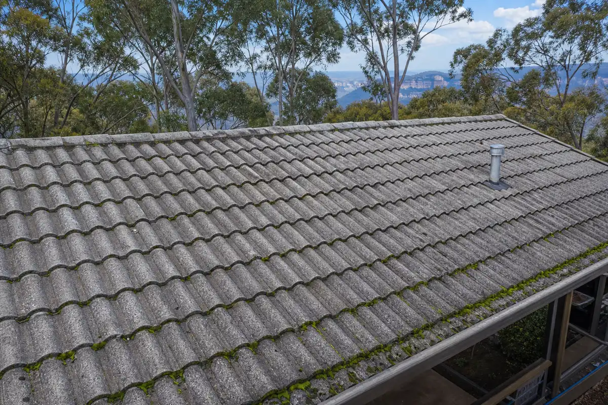 Weathered concrete tile roof on a Blue Mountains home with faded coating and moss on the shaded courses